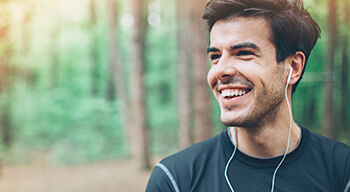 man in forest smiling with headphones in