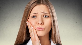 Frowning woman touching her cheek