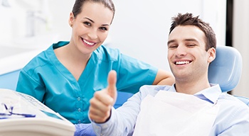 Smiling man in dental chair giving thumbs up