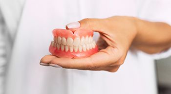 Dentist holding full dentures in Somerville