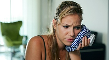 Concerned woman holding cold compress against her cheek