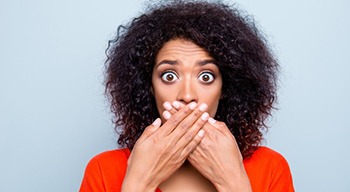 woman with shocked expression covering her mouth 