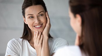 a woman smiling and touching her smooth face