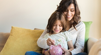 parent and child putting money in a savings bank