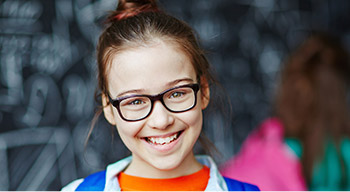 young girl smiling with glasses and backpack