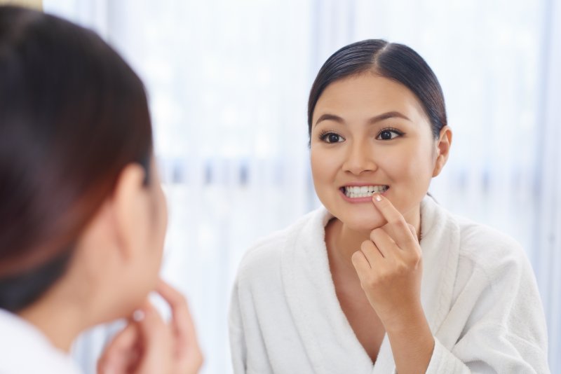 Woman checking teeth in mirror 