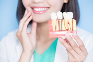 Dentist holding a dental implant model while touching her jaw