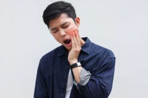 Man opening mouth and touching hand to his jaw in pain